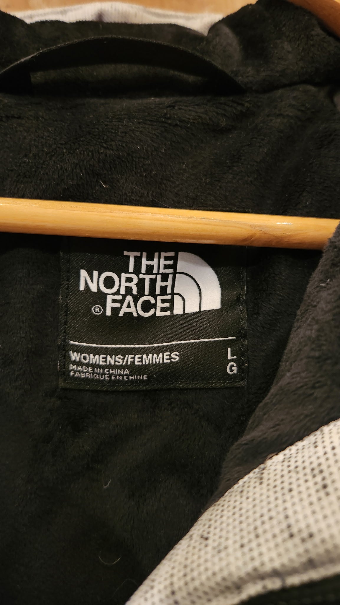 Black jacket with The North Face label on a wooden stick